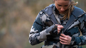 Front of Hunter Zipping Up Women's Pro Merino 200 under Women's Peloton 240 Full Zip Hoodie in Vias Camouflage