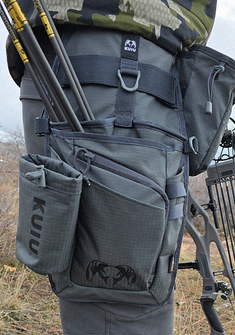 Close-up profile of KUIU Archery Hip Quiver in Gunmetal Grey secured to a person's right leg, highlighting the compartments and attachment straps.