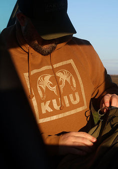 Front, Angled View of Hunter in Truck Wearing Topo Box Hoodie in Saddle Color
