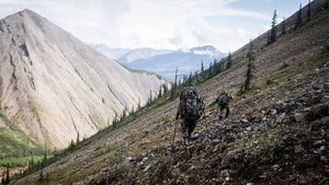Two hunters hiking along a rocky slope wearing Vias Camouflage