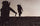 Silhoutte of two hunters climbing uphill through rock shale