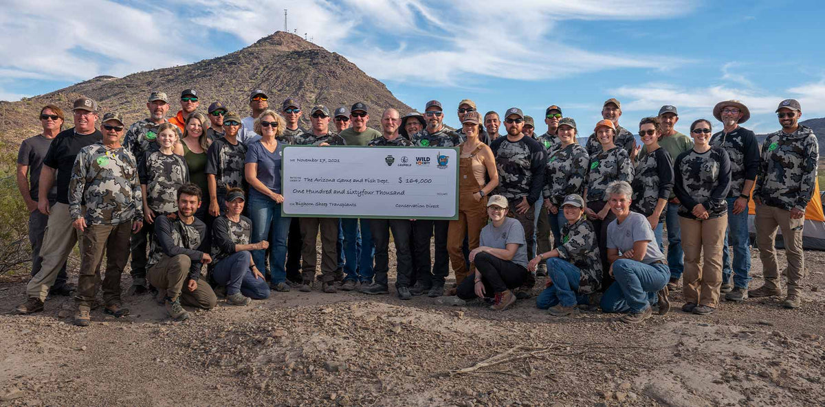 Volunteers standing around holding the donation check from Conservation Direct that was given to fund the Arizona wild sheep management budget