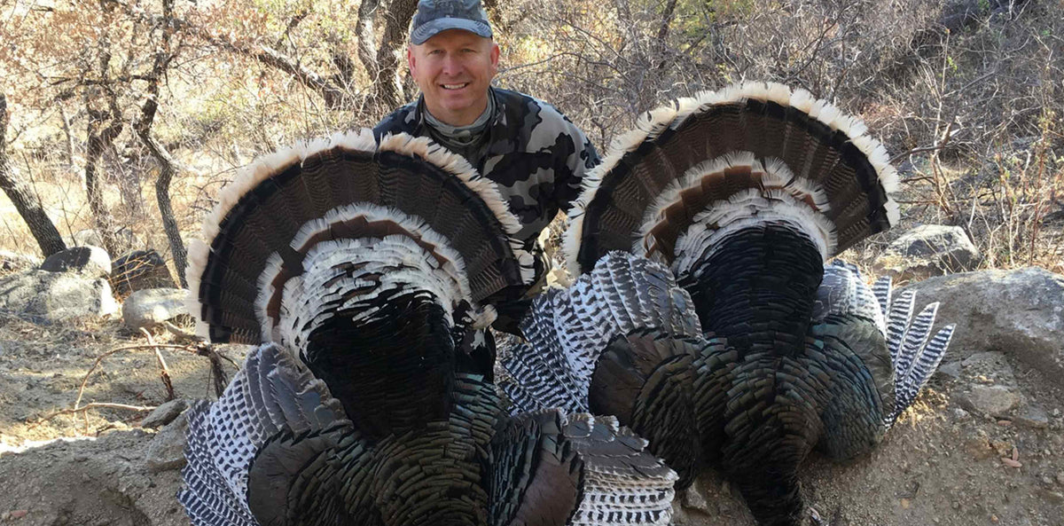 Turkey hunter posing with two Gould's Turkeys