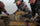 Workers in vias camouflage holding down a bighorn ram while blood is drawn and vaccinations are administered