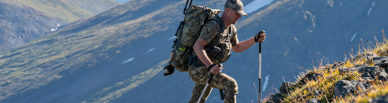 Hunter in an outdoor setting, using a binocular, wearing a PRO Merino 200 Zip-T Hoodie in Vias Camouflage