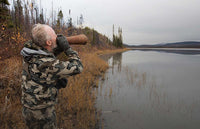 Hunter in Vias camoufalge calling moose along the side of a lake