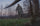 Hunter Holding Bow Walking Up to Harvested Whitetail Buck in Green Field Wearing Full Valo Camouflage