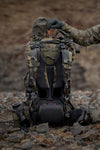 Person in camouflage gear with a backpack on rocky terrain