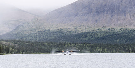 Water aircraft landing on a lake with mountains in the distance